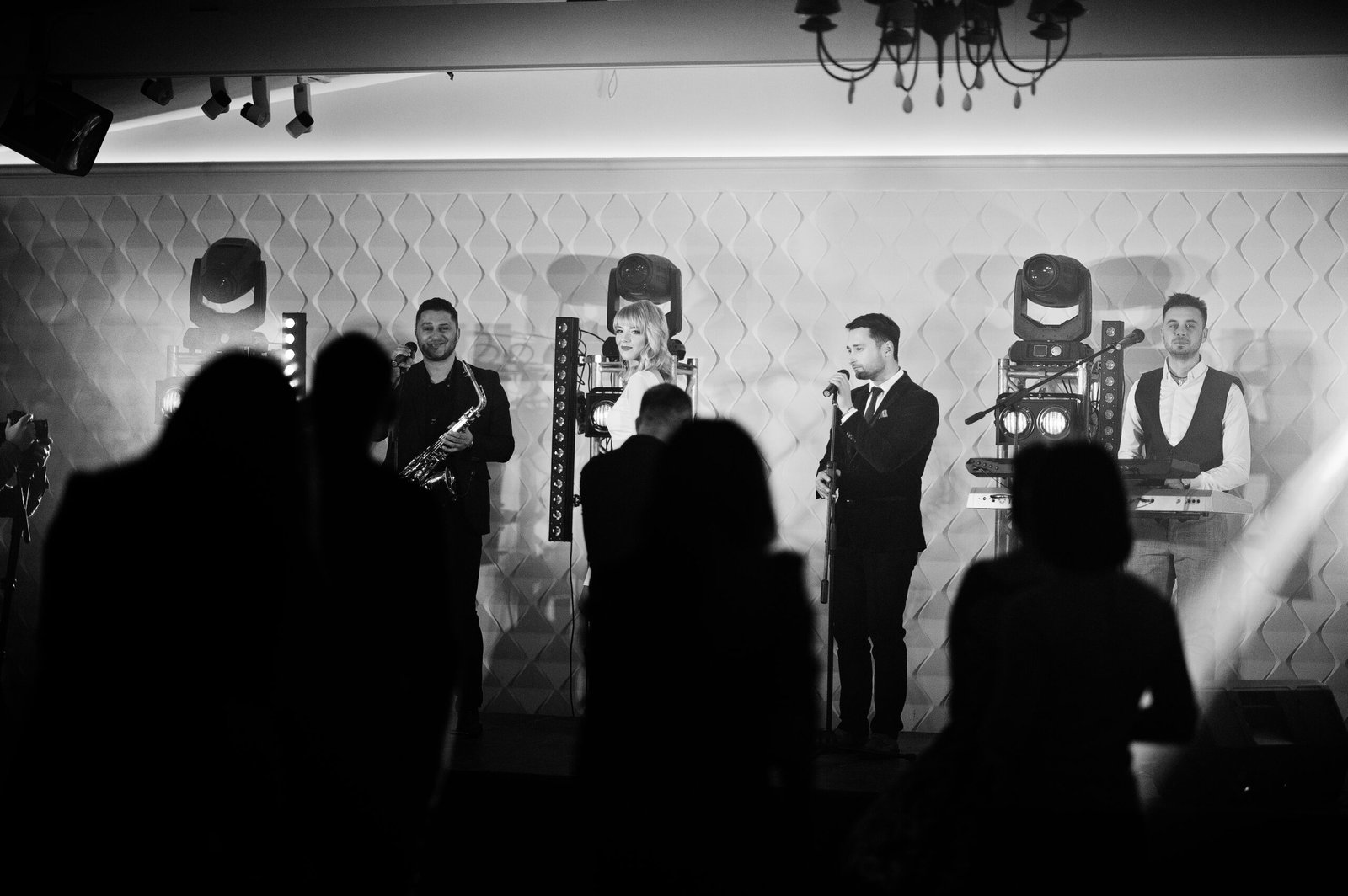 Musicial music live band performing on a stage with different lights with crowd of people fans.