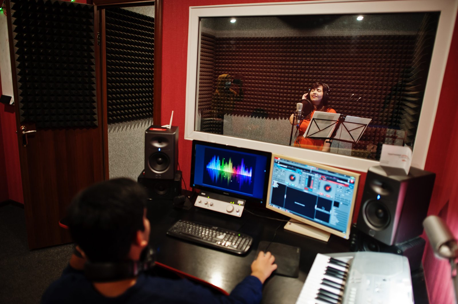 Young asian singer with microphone recording song in record music studio with sound producer.